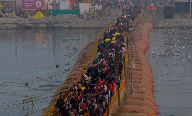 FILE - Indian Hindu devotees cross a bridge as they return after a holy dip on Mauni Amavasya, a divine occasion in Hindu religious practice followed for honoring ancestors or forefathers, at the Sangam, the confluence of the Ganges, the Yamuna and the mythical Saraswati rivers, during the annual month long Hindu religious fair "Magh Mela" in Prayagraj, India, Jan. 18, 2026. (AP Photo/Rajesh Kumar Singh), File