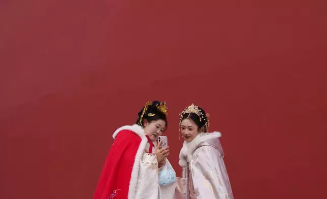 FILE - Visitors take pictures of a snow-covered Forbidden City, in Beijing, China, Jan. 18, 2026. (AP Photo/Vincent Thian, File)
