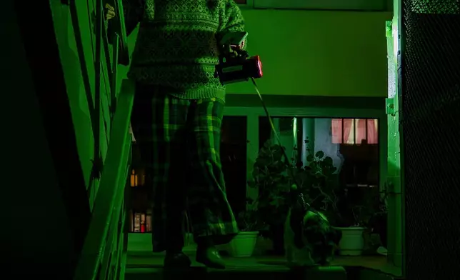 FILE - Tetiana Tatarenkova shines a flashlight as she goes to see her neighbour during a blackout caused by Russia's regular air attacks against the country's energy infrastructure in Kyiv, Ukraine, Jan. 13, 2026. (AP Photo/Dan Bashakov, File)