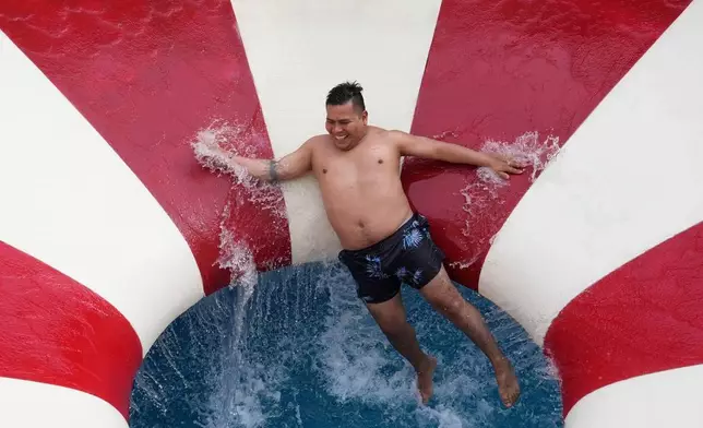 FILE A man tumbles down a water slide in a public pool in the Puente Piedra district outside of Lima, Peru, Jan. 18, 2026. (AP Photo/Martin Mejia, File)