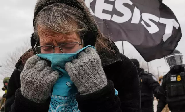 FILE - A woman covers her face from tear gas as federal immigration officers confront protesters outside Bishop Henry Whipple Federal Building, Jan. 15, 2026, in Minneapolis. (AP Photo/Adam Gray, File)
