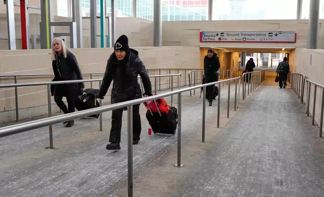 Travelers walk up a salt-covered sidewalk that lead into the main concourse at Love Field Airport Saturday, Jan. 24, 2026, in Dallas. (AP Photo/Tony Gutierrez)