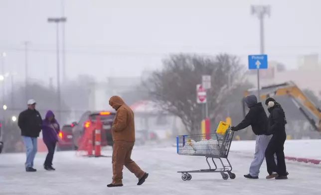 Shoppers brave cold weather as they walk in the parking lot of a store during a winter storm Saturday, Jan. 24, 2026, in Arlington, Texas. (AP Photo/Julio Cortez)