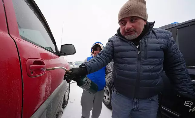 Ignacio Rodriguez uses a torch in an attempt to thaw the frozen door of a pickup belonging to his brother Adrian Rodriguez, not visible, during a winter storm Saturday, Jan. 24, 2026, in Arlington, Texas. (AP Photo/Julio Cortez)