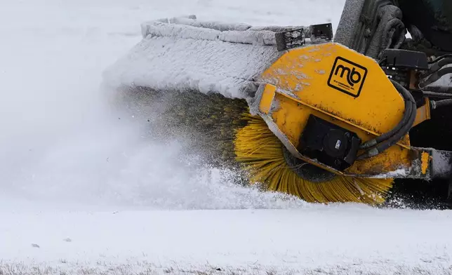 A plow clears snow from a snow-covered sidewalk during a cold day in Lake Forest, Ill., Wednesday, Jan. 21, 2026. (AP Photo/Nam Y. Huh)