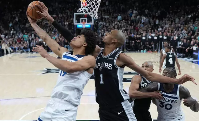 Minnesota Timberwolves forward Joan Beringer (19) is blocked by San Antonio Spurs forward Victor Wembanyama (1) as he drives to the basket during the second half of an NBA basketball game in San Antonio, Saturday, Jan. 17, 2026. (AP Photo/Eric Gay)
