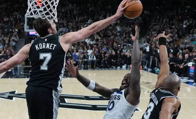 Minnesota Timberwolves forward Julius Randle, center, is blocked by San Antonio Spurs center Luke Kornet (7) during the second half of an NBA basketball game in San Antonio, Saturday, Jan. 17, 2026. (AP Photo/Eric Gay)