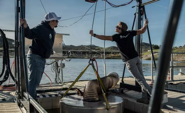 Jaden Gilliam, OceanWell project engineer, left, and Mark Golay, director of engineering projects, lower a prototype reverse osmosis pod into Las Virgenes Reservoir in Westlake Village, Calif., Monday, Dec. 1, 2025. (AP Photo/Annika Hammerschlag)