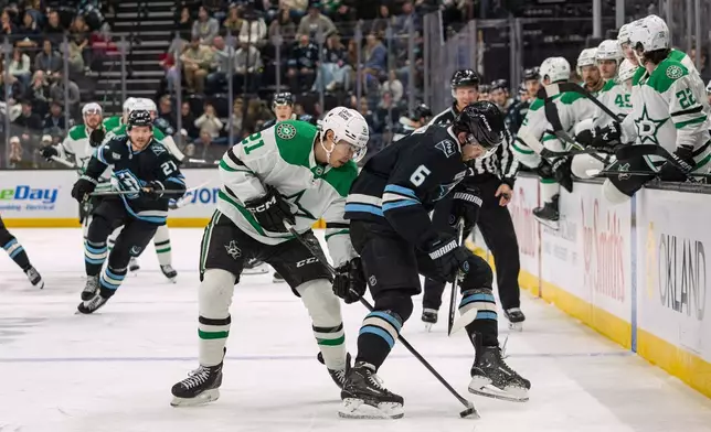 Dallas Stars left wing Jason Robertson, center left, fights for the puck against Utah Mammoth defenseman John Marino (6) during the second period of an NHL hockey game, Thursday, Jan. 15, 2026, in Salt Lake City. (AP Photo/Melissa Majchrzak)
