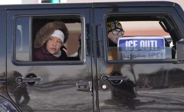 People ride in a car during a caravan protest, Monday, Jan. 19, 2026 in St. Paul, Minn. (AP Photo/Angelina Katsanis)