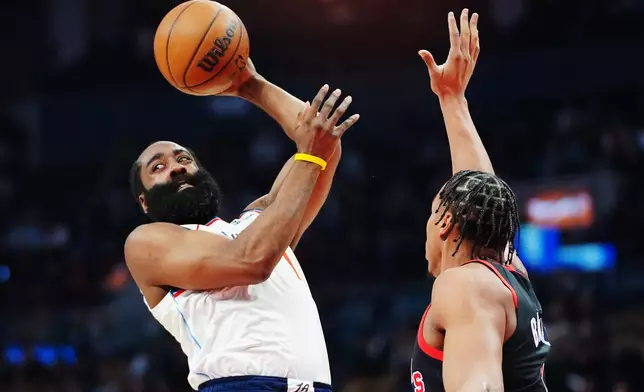 Los Angeles Clippers' James Harden, left, looks to pass the ball over Toronto Raptors' Scottie Barnes, right, during first-half NBA basketball game action in Toronto, Friday, Jan. 16, 2026. (Frank Gunn/The Canadian Press via AP)