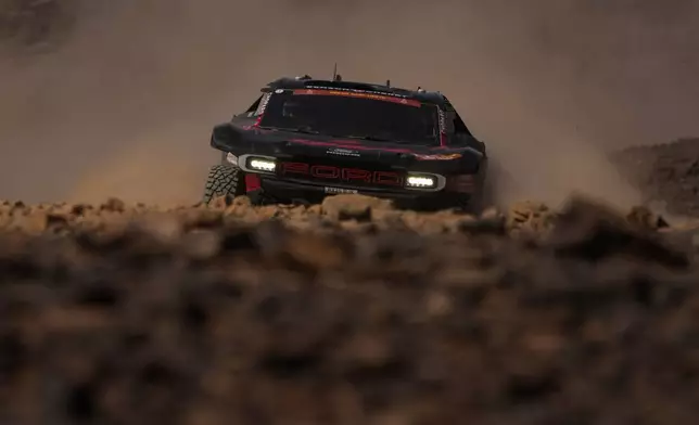 Driver Romain Dumas and co-driver Alex Winocq compete with riders David Brock, right, and Fernando Dominguez, in the background, during the eighth stage of the Dakar Rally with a start and finish at Wadi Ad Dawasir, Saudi Arabia, Monday, Jan.12, 2026. (AP Photo/Thibault Camus)