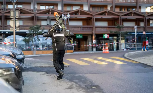 A skier walks in the area where a fire broke out at the Le Constellation bar and lounge leaving people dead and injured, during New Year’s celebration, in Crans-Montana, Swiss Alps, Switzerland, Thursday, Jan. 1, 2026. (Alessandro della Valle/Keystone via AP)