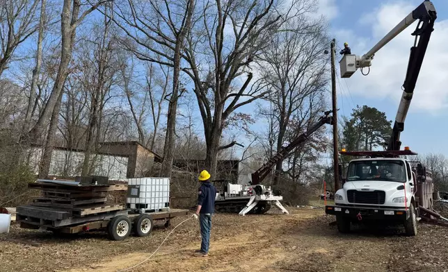 Ethan Green, 21, left, an apprentice one lineman at the Yazoo Valley Power Association, looks up at a crew member Taylor Arinder on Friday, Jan. 30, 2026 in Bentonia, Miss. (AP Photo/Sophie Bates)