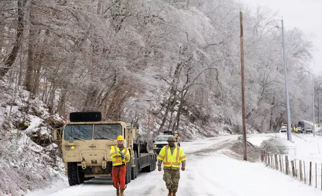 Tennessee National Guard members Taylor Osteen, left, and Antuwan Powell walk along an ice covered road as they work to remove trees Friday, Jan. 30, 2026, in Nashville, Tenn. (AP Photo/George Walker IV)
