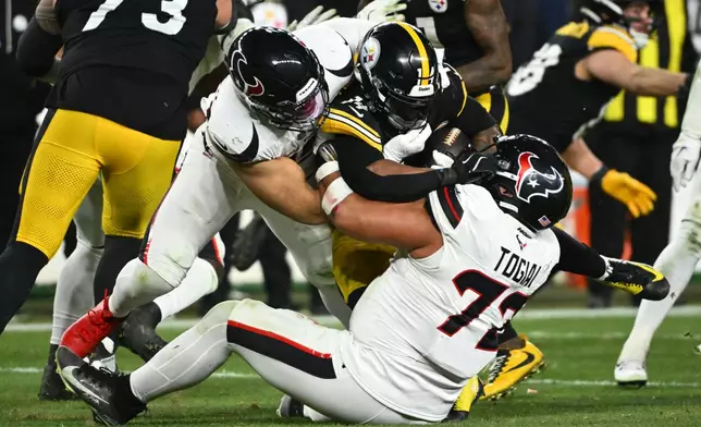 Pittsburgh Steelers running back Kenneth Gainwell is tackled by Houston Texans linebacker Henry To'oto'o, left, and defensive tackle Tommy Togiai (72) during the second half of an NFL wild-card playoff football game, Monday, Jan. 12, 2026, in Pittsburgh. (AP Photo/Justin Berl)