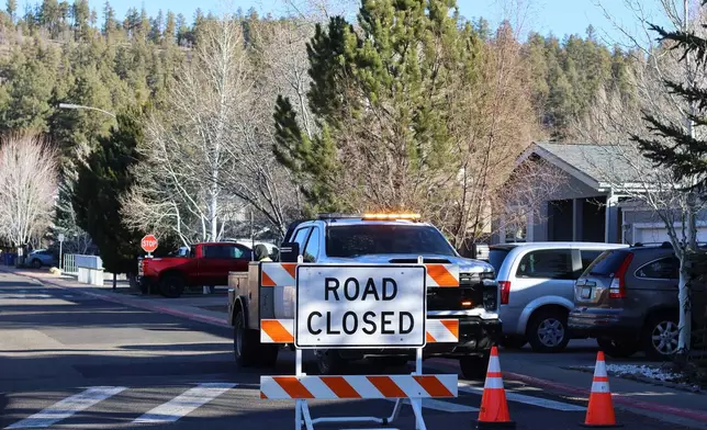 The blocked road to a neighborhood in Flagstaff, Arizona, where police say a man opened fire at officers is seen Thursday, Feb. 5, 2026. (AP Photo/Cheyanne Mumphrey)