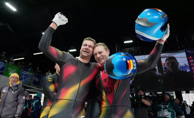Germany's gold medalists Johannes Lochner, left, and Germany's silver medalist Francesco Friedrich, right, celebrate at the finish after the four man bobsled competition at the 2026 Winter Olympics, in Cortina d'Ampezzo, Italy, Sunday, Feb. 22, 2026. (AP Photo/Alessandra Tarantino)
