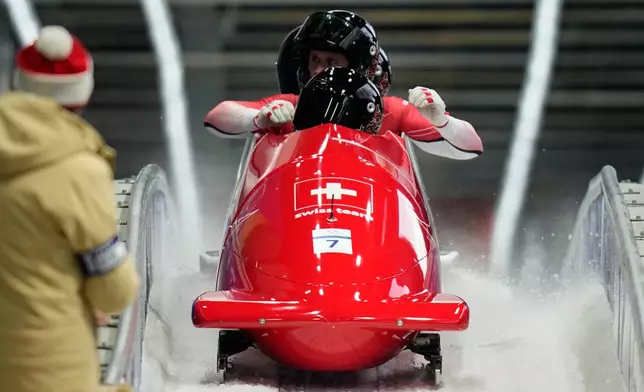 Switzerland's Michael Vogt, front Andreas Haas, Amadou David Ndiaye and Mario Aeberhard arrive at the finish during a four man bobsled run at the 2026 Winter Olympics, in Cortina d'Ampezzo, Italy, Sunday, Feb. 22, 2026. (AP Photo/Aijaz Rahi)