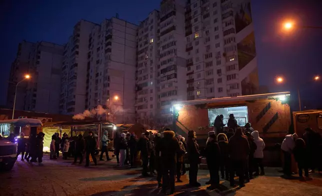 People stand in line for free hot meals that veterans of the 3rd Separate Assault Brigade of Ukraine's Armed Forces serve in residential neighborhood as repeated Russian air attacks on the country's energy sector leave people without power, heating and water in the harshest winter in decades in Kyiv, Ukraine, Sunday, Feb. 8, 2026. (AP Photo/Efrem Lukatsky)