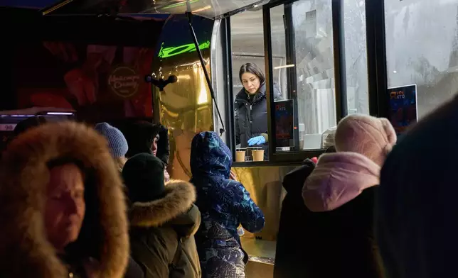 People stand in line for free hot meals that veterans of the 3rd Separate Assault Brigade of Ukraine's Armed Forces serve in residential neighborhood as repeated Russian air attacks on the country's energy sector leave people without power, heating and water in the harshest winter in decades in Kyiv, Ukraine, Sunday, Feb. 8, 2026. (AP Photo/Efrem Lukatsky)