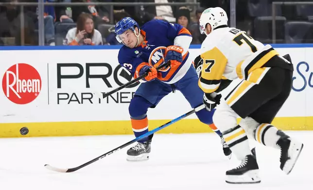 New York Islanders center Mathew Barzal, left, shoots the puck past Pittsburgh Penguins defenseman Brett Kulak (77) during the second period of an NHL hockey game, Tuesday, Feb. 3, 2026, in Elmont, N.Y. (AP Photo/Heather Khalifa)