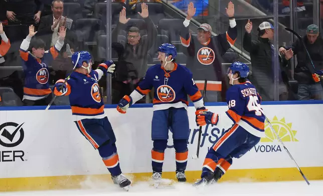 The New York Islanders' Mathew Barzal, center, and Matthew Schaefer (48) celebrate a goal by Bo Horvat, left, to win against the Pittsburgh Penguins during the overtime period of an NHL hockey game, Tuesday, Feb. 3, 2026, in Elmont, N.Y. (AP Photo/Heather Khalifa)