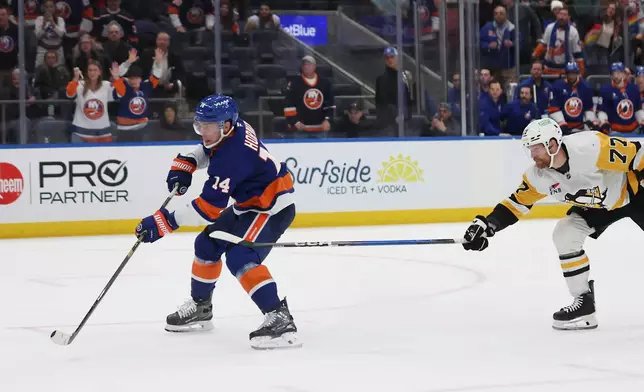New York Islanders center Bo Horvat (14) scores past Pittsburgh Penguins defenseman Brett Kulak (77) during the overtime period of an NHL hockey game, Tuesday, Feb. 3, 2026, in Elmont, N.Y. (AP Photo/Heather Khalifa)