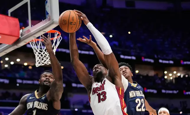 Miami Heat center Bam Adebayo (13) goes to the basket between New Orleans Pelicans forward Zion Williamson (1) and center Derik Queen (22) in the second half of an NBA basketball game, Wednesday, Feb. 11, 2026, in New Orleans. (AP Photo/Gerald Herbert)