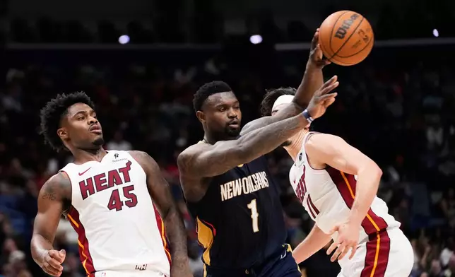 New Orleans Pelicans forward Zion Williamson (1) passes around Miami Heat guard Davion Mitchell (45) in the first half of an NBA basketball game, Wednesday, Feb. 11, 2026, in New Orleans. (AP Photo/Gerald Herbert)