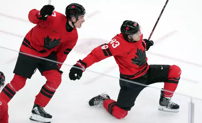 Canada's Mitch Marner (93) and Macklin Celebrini (17) celebrate after Marner scored the winning goal during the overtime period of a men's ice hockey quarterfinal game between Canada and Czechia at the 2026 Winter Olympics, in Milan, Italy, Wednesday, Feb. 18, 2026. (AP Photo/Carolyn Kaster)