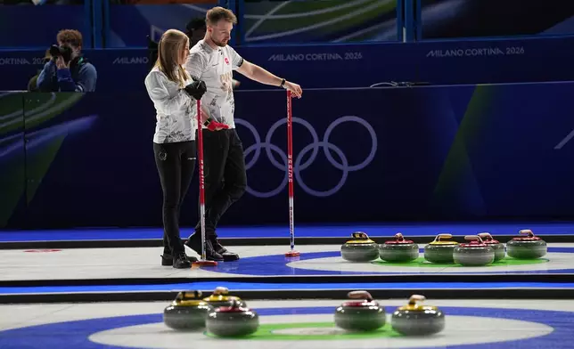 Switzerland's Briar Schwaller-Huerlimann and Yannick Schwaller look at the stones, during the mixed doubles round robin phase of the curling competition against Estonia, at the 2026 Winter Olympics, in Cortina d'Ampezzo, Italy, Wednesday, Feb. 4, 2026. (AP Photo/Fatima Shbair)
