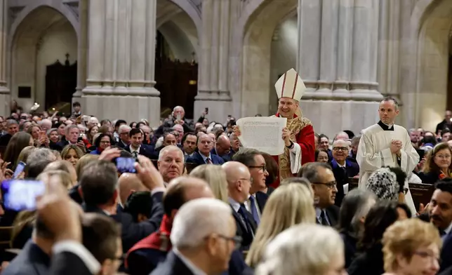 Archbishop Ronald Hicks shows the apostolic letter to the congregation after receiving it from Cardinal Christophe Pierre, apostolic nuncio to the United States, during the Mass of Installation at St. Patrick's Cathedral, Friday, Feb. 6, 2026, in New York. (AP Photo/Stefan Jeremiah)
