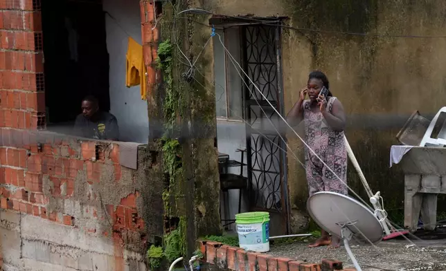 Residents watch firefighters and civil defense workers help at the site where homes collapsed due to heavy rains and severe flooding in the Parque Burnier neighborhood of Juiz de Fora in Minas Gerais state, Brazil, Tuesday, Feb. 24, 2026. (AP Photo/Silvia Izquierdo)