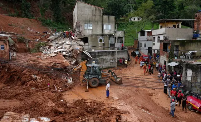Firefighters and civil defense workers help at the site where homes collapsed due to heavy rains and severe flooding in the Parque Burnier neighborhood of Juiz de Fora in Minas Gerais state, Brazil, Tuesday, Feb. 24, 2026. (AP Photo/Silvia Izquierdo)