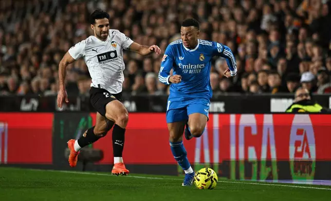 Real Madrid's Kylian Mbappe, right, and Valencia's Eray Comert challenge for the ball during the Spanish La Liga soccer match between Valencia and Real Madrid in Valencia, Spain, Sunday, Feb. 8, 2026. (AP Photo/Francisco Macia)