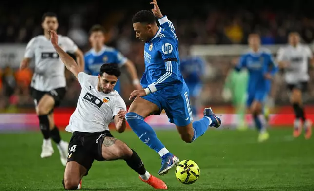 Real Madrid's Kylian Mbappe, centre, and Valencia's Eray Comert challenge for the ball during the Spanish La Liga soccer match between Valencia and Real Madrid in Valencia, Spain, Sunday, Feb. 8, 2026. (AP Photo/Francisco Macia)