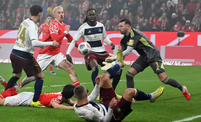 Mainz's Phillip Tietz, second left, and goalkeeper Hamburger's Daniel Heuer Fernandes, right, in action during the Bundesliga soccer match between Mainz 05 and Hamburger SV in Mainz, Germany, Friday Feb. 20, 2026. (Torsten Silz/dpa via AP)