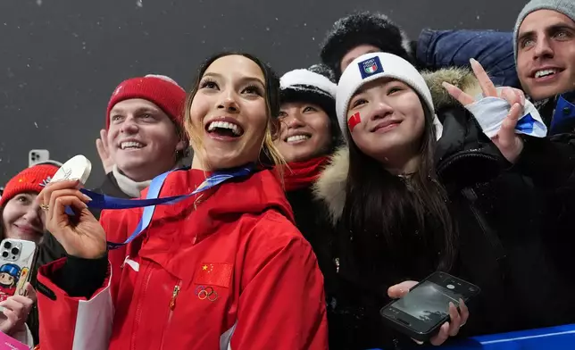 Silver medalist China's Eileen Gu celebrates with fans after the women's freestyle skiing big air finals at the 2026 Winter Olympics, in Livigno, Italy, Monday, Feb. 16, 2026. (AP Photo/Gregory Bull)