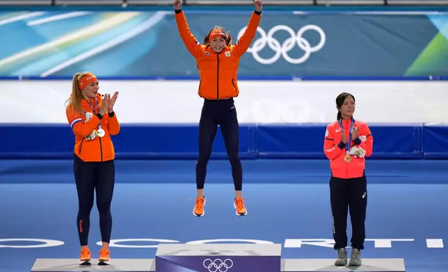 Femke Kok of the Netherlands, center and gold medal celebrates with Jutta Leerdam of the Netherlands, left and silver medal, and Miho Takagi of Japan, right and bronze medal, on the podium of the women's 500 meters speedskating race at the 2026 Winter Olympics, in Milan, Italy, Sunday, Feb. 15, 2026. (AP Photo/Luca Bruno)