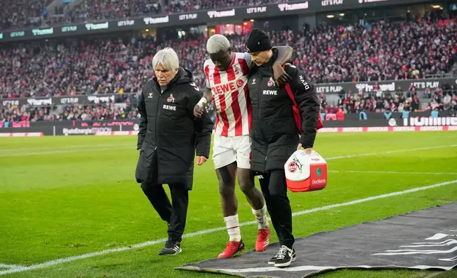 Cologne's Ragnar Ache is helped off the pitch during a German Bundesliga soccer match between Cologne and Leipzig in Cologne, Germany, Sunday, Feb. 8, 2026. (AP Photo/Martin Meissner)