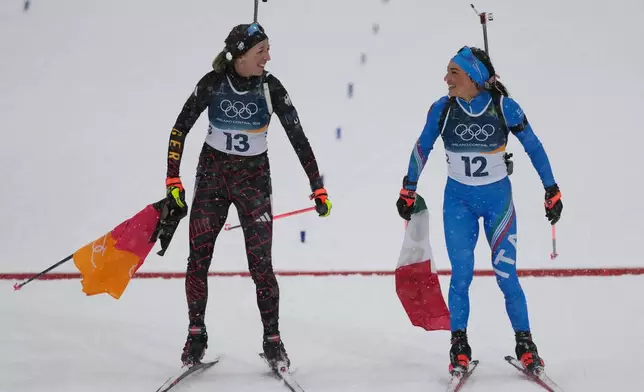 Franziska Preuss, of Germany, and Dorothea Wierer, of Italy, who both announced their retirement from the sport, celebrate after the women's 12.5-kilometer mass start biathlon race at the 2026 Winter Olympics in Anterselva, Italy, Saturday, Feb. 21, 2026. (AP Photo/Mosa'ab Elshamy)