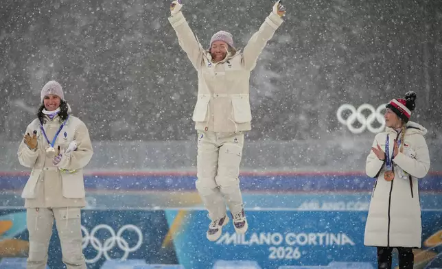 Gold medalist Oceane Michelon, of France, center, jumps on the podium during a victory ceremony next to silver medalist Julia Simon, of France, left, and bronze medalist Tereza Vobornikova, of Czechia, after the women's 12.5-kilometer mass start biathlon race at the 2026 Winter Olympics in Anterselva, Italy, Saturday, Feb. 21, 2026. (AP Photo/Andrew Medichini)