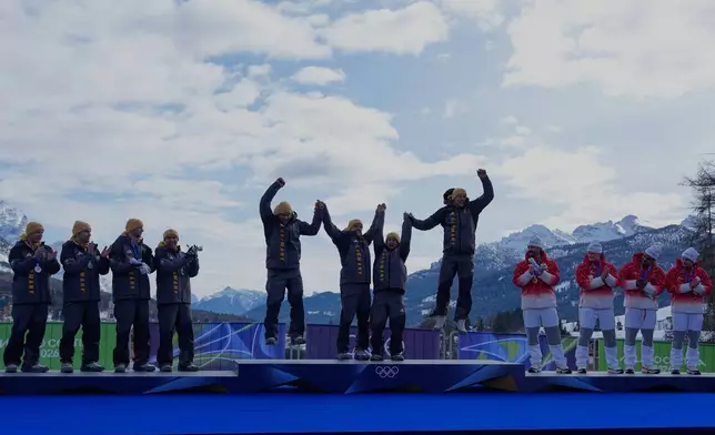 From left, Germany's silver medal team Francesco Friedrich, Matthias Sommer, Alexander Schuller and Felix Straub, Germany's gold medal team Johannes Lochner, Thorsten Margis, Jorn Wenzel and Georg Fleischauer and Switzerland's bronze medalists Michael Vogt, Andreas Haas, Amadou David Ndiaye and Mario Aeberhard take celebrate on the podium of the four man bobsled competition at the 2026 Winter Olympics, in Cortina d'Ampezzo, Italy, Sunday, Feb. 22, 2026.(AP Photo/Alessandra Tarantino)