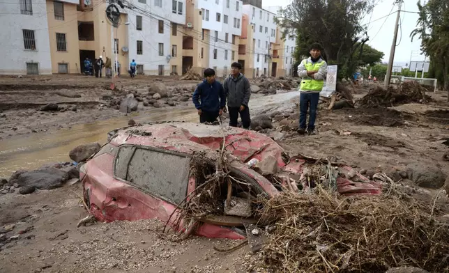 People inspect the road destroyed by heavy rain that triggered flooding in Arequipa, Peru, Monday, Feb. 23, 2026. (AP Photo/Jose Sotomayor)