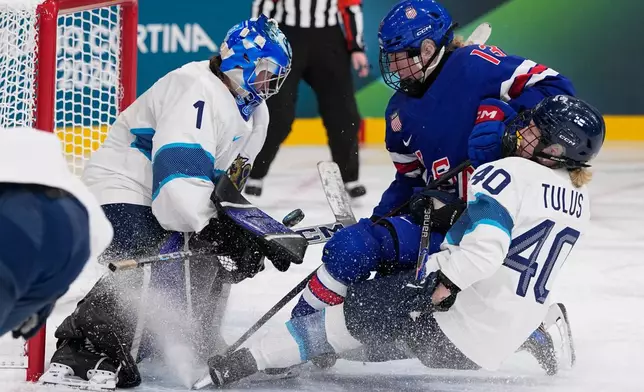 Finland's Sanni Ahola and Finland's Noora Tulus, right, make a save against United States' Grace Zumwinkle during a preliminary round match of women's ice hockey between the United States and Finland at the 2026 Winter Olympics, in Milan, Italy, Saturday, Feb. 7, 2026. (AP Photo/Petr David Josek)