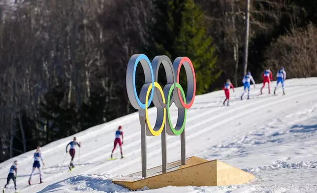 Athletes ski past the Olympic rings during the cross country skiing women's 50km mass start classic at the 2026 Winter Olympics, in Tesero, Italy, Sunday, Feb. 22, 2026. (AP Photo/Matthias Schrader)