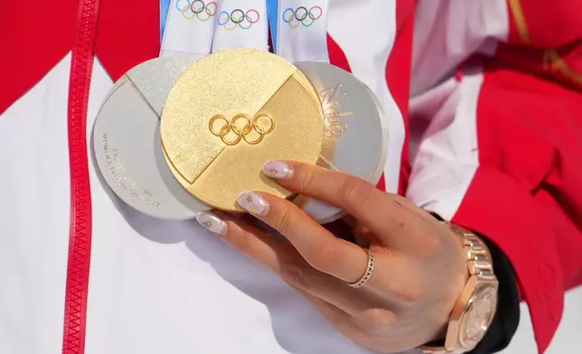 China's Eileen Gu holds her gold medal alongside her two silver medals after the women's freestyle skiing halfpipe final at the 2026 Winter Olympics, in Livigno, Italy, Sunday, Feb. 22, 2026. (AP Photo/Lindsey Wasson)