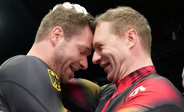 Germany's gold medalists Johannes Lochner, left, and Germany's silver medalist Francesco Friedrich, right, celebrate at the finish after the four man bobsled competition at the 2026 Winter Olympics, in Cortina d'Ampezzo, Italy, Sunday, Feb. 22, 2026. (AP Photo/Alessandra Tarantino)