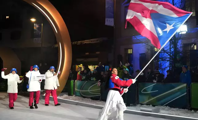 Kellie Delka, flag bearer of Puerto Rico, leads her team in during the Olympic opening ceremony at the 2026 Winter Olympics, in Cortina d'Ampezzo, Italy, Friday, Feb. 6, 2026. (AP Photo/Misper Apawu)